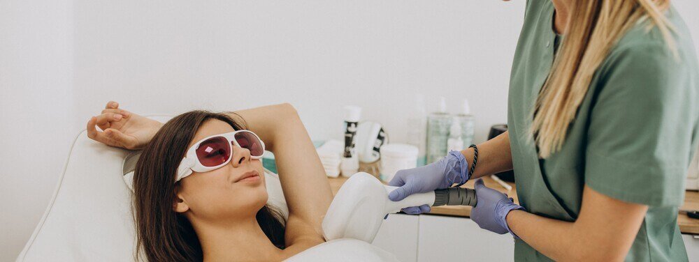 Mo&ccedil;a deitada recebendo tratamento est&eacute;tico de depila&ccedil;&atilde;o a laser
